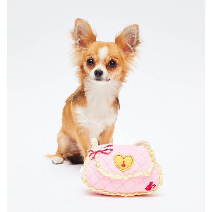 A dog posing with a toy that looks like a handbag