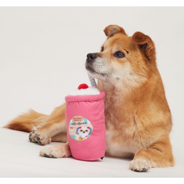 A dog lying down with a milkshake dog toy